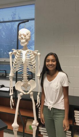 Leader of HOSA, Amani Patel poses next to a skeleton in Mr. Goulds room where much of the clubs activities take place. 