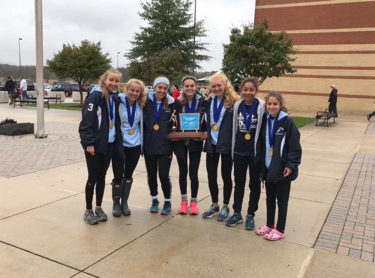 The girls pose with their trophy and medals under the rainy sky after the district meet. The team won first place, and many of the girls won individual medals as well. 