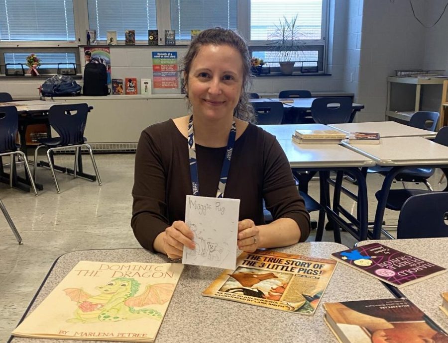 Ms. Bonanni, one of the creative writing teachers, holding a student-made picture book with another student book on the left.  