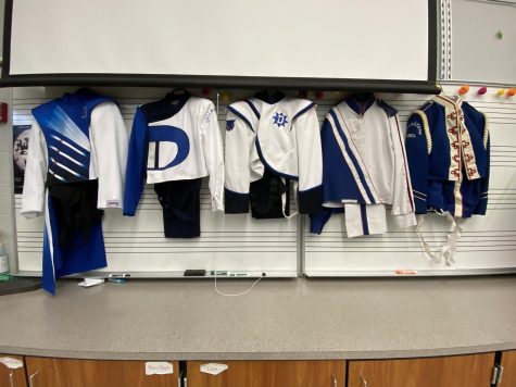 All of the past band uniforms are lined up with the new band uniforms on the left and the oldest band uniforms on the right. 