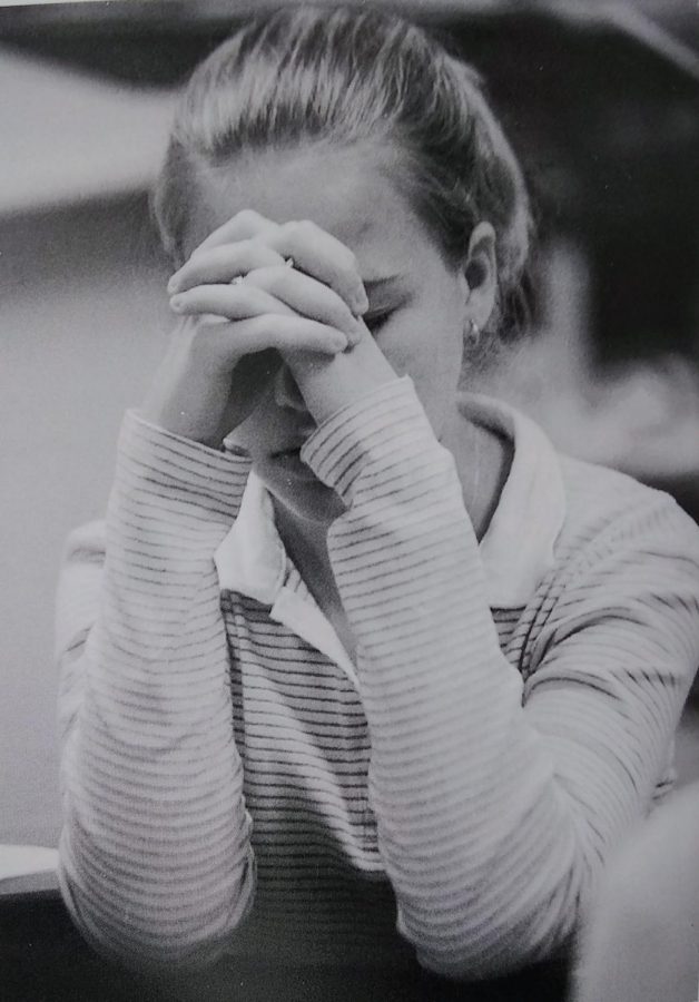 A student spends time in prayer during a club meeting.
