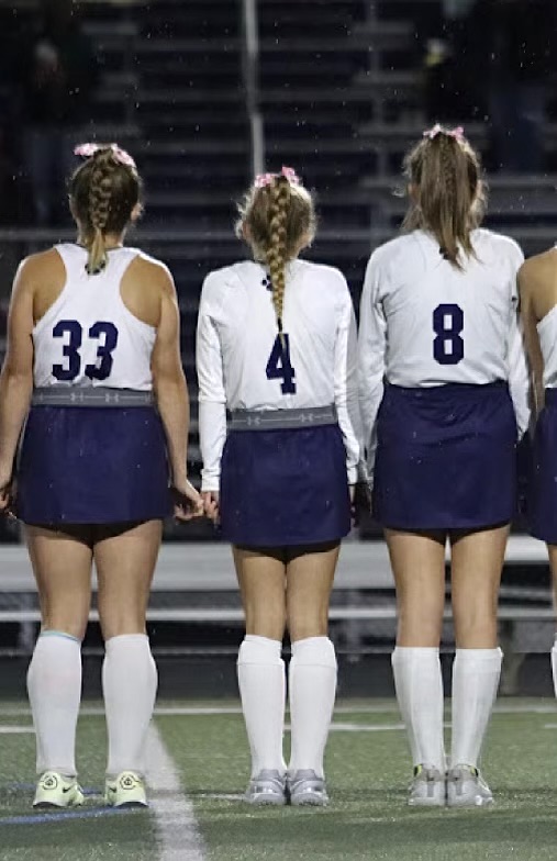 Freshmen Anna Roperti (33), Ella Zorbaugh (4) and Emmerson Markel (8) standing for The Star-Spangled Banner holding each others pinkies, which the team does at every game to symbolize they are united.