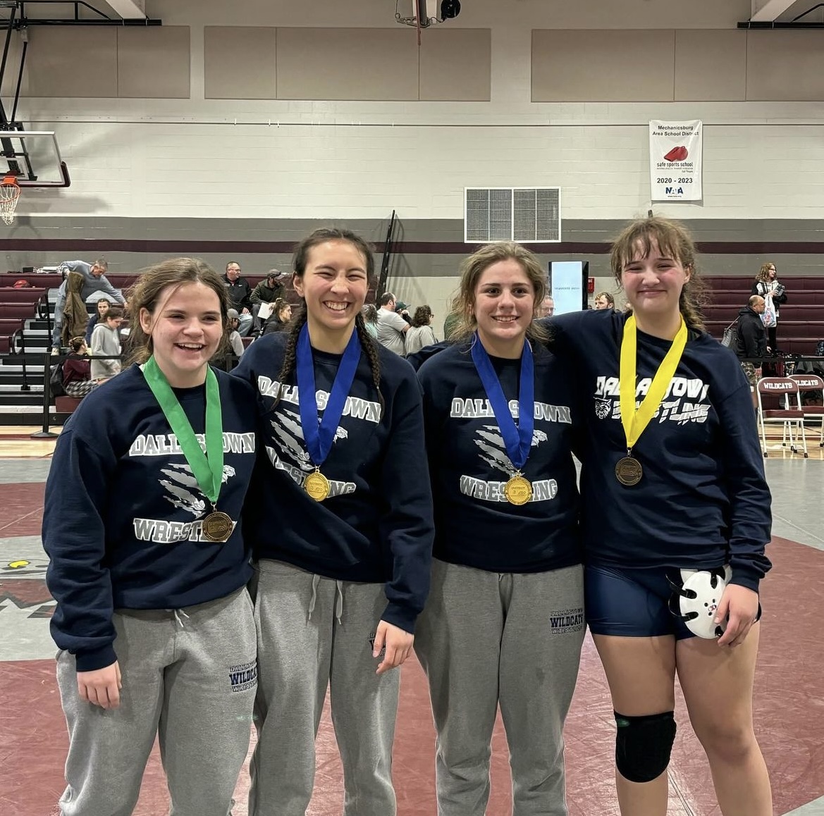 Avery Baldwin, Kenna Hoffman, Shelly Gipson-McDonald, and Tessa Henise (left to right) posing with their medals after representing Dallastown at sectionals. Baldwin and Hoffman went on to qualify for the PIAA tournament.  Photo via Dallastown Girls Wrestling Instagram. 
