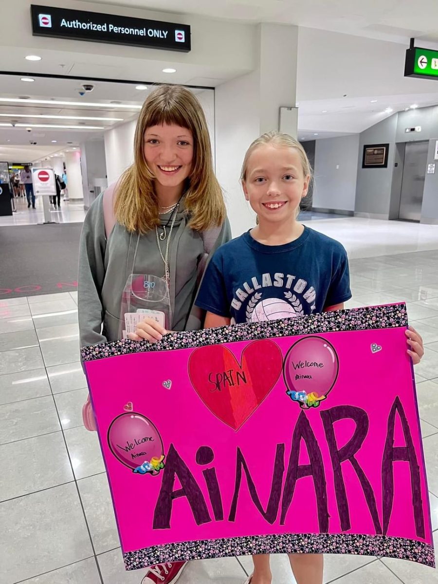 Lexie Harbert greeting Ainara Serrano Fraile with a sign at the airport.