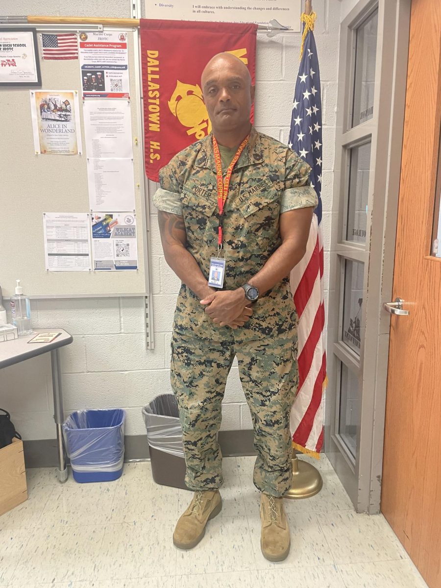 GySgt. Porter standing in front of the MCJROTC flag in his classroom.