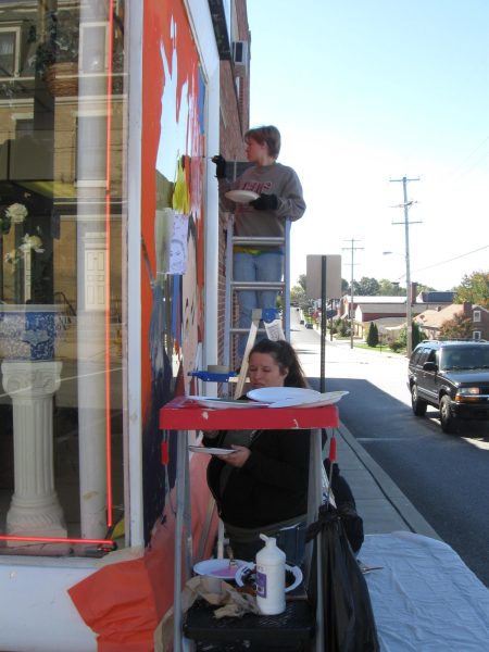 Art class students painting a Halloween based mural on the side of Roma's Pizza.