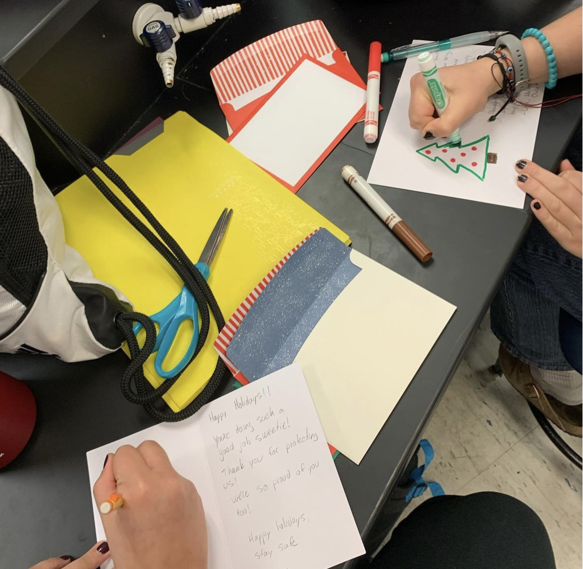 Students in scrapbooking club are using different materials to create letters. The letters will go to the troops.