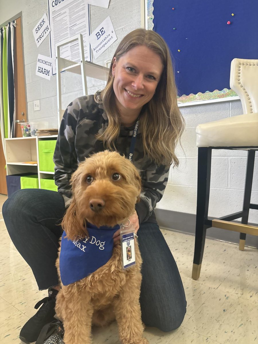 Counselor Mrs Bouchillon sits with Max the new therapy dog at DHS. In the picture you can see he even earned his own badge.