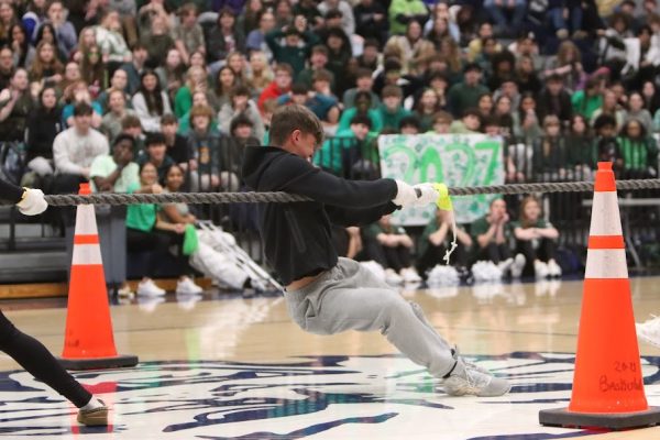 Freshmen representative pulling the tug of war rope with their hands past the yellow marker.