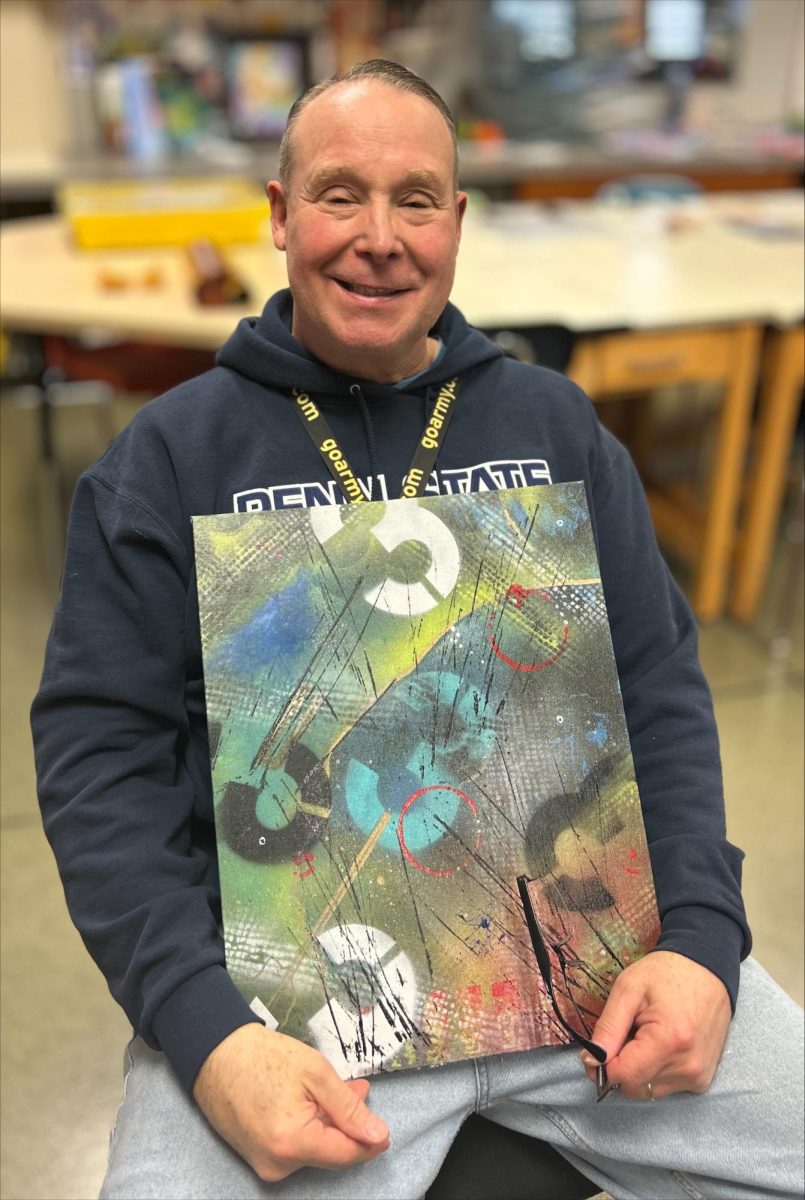 DAHS art teacher, Mr. Myers holds an example artwork for his painting 1 class.