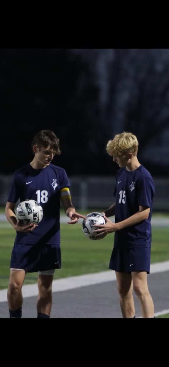 Logan Ungerland (left) showing Ethan Zorbaugh (right) how to tell the game balls apart from the practice balls. 