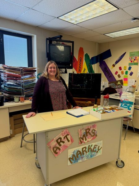 Elementary art teacher, Mrs. Markey, stands at her classroom desk at York Township.