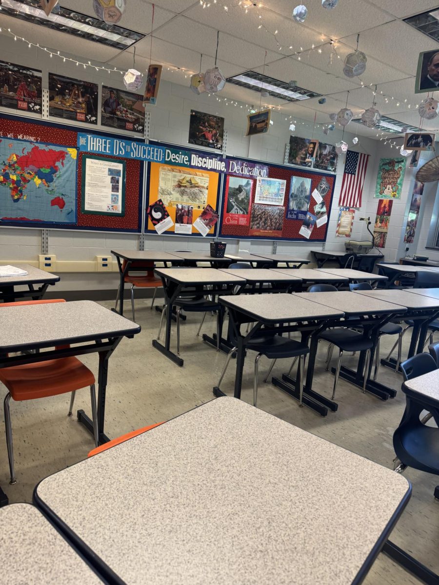 A classroom with colorful signs about different religions hanging on the walls with desks neatly set up in rows of three.