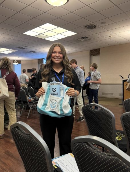 Girl in black holding and bag and a water bottle in front of her.